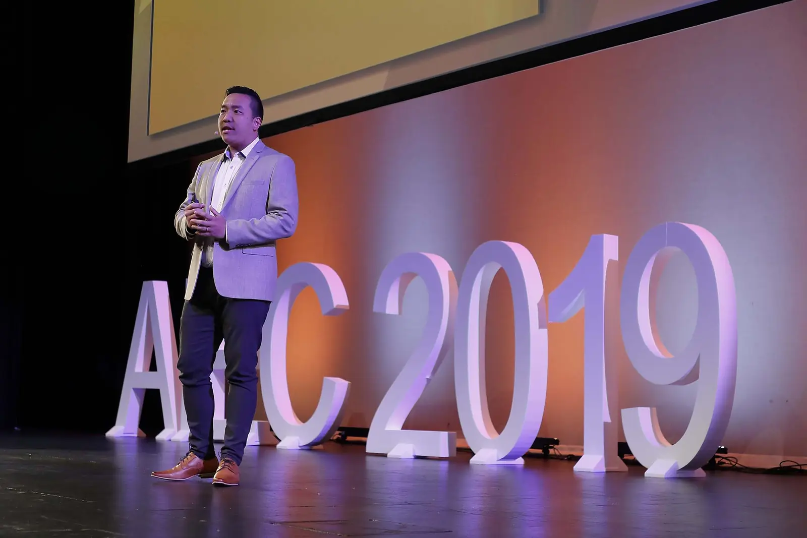 William Ndut speaking on stage — moment 04